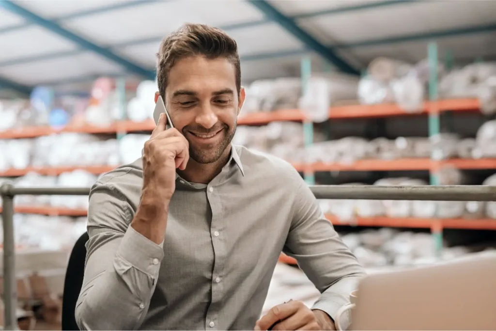 Relaxed Small Business Warehouse Manager on Phone with Customer Support for Shipping Solution