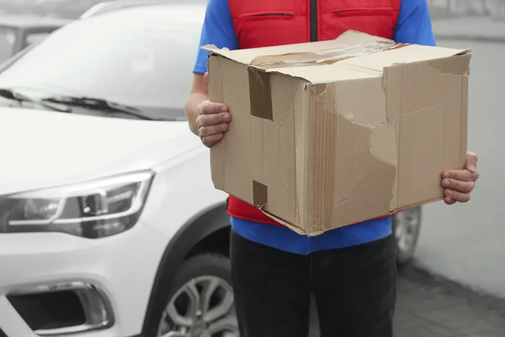 A delivery person holding a damaged parcel covered by ecommerce shipping insurance.