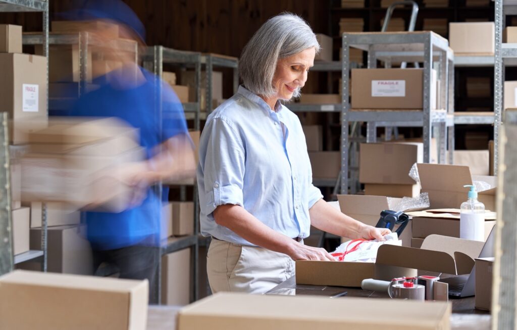 Experienced ecommerce operations manager packing a shipment in a busy warehouse, thinking about the best way to save on shipping.